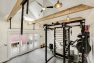 A home gym in a converted garage with high-ceilings and timber beams.