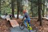 Gravel and boardwalk paths that are part of a bike skills area wind around larger, mature trees.