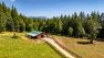 An aerial view of Pasado’s Safe Haven’s new cow barn. The barn has a green roof, a long driveway, and is surrounded by pasture for the cows.