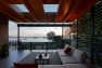 The covered deck at the house looking out over Puget Sound. There is a large sectional couch with a coffee table and rug under the cover of the deck.