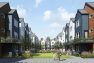 A digital rendering of Stone Avenue Townhomes, a townhome and mid-rise multifamily development in Seattle, Washington. This view shows a lane with pedestrians walking along it, There is a green area behind them surrounded by townhomes in white and blue with gable roofs.